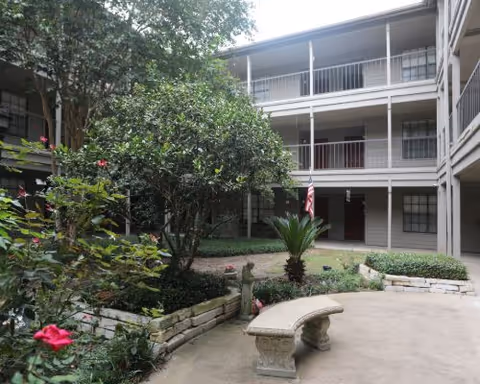 Three-story covered courtyard with a planted garden, stone bench, and surrounding balcony walkways.