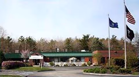 Exterior view of Maine Veterans' Homes Scarborough with flags and a driveway.