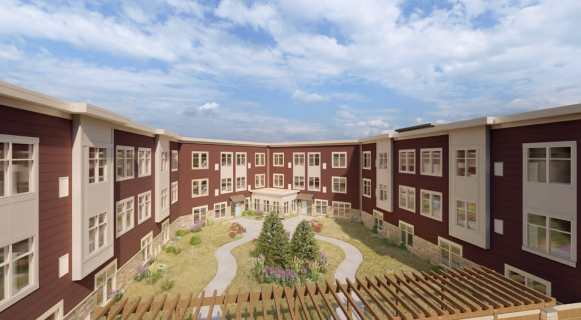 Red and beige three-story building surrounding a landscaped central courtyard with winding paths, greenery, and a wooden pergola under a partly cloudy sky.