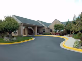 Front view of a senior care facility with driveway and landscaped entrance.