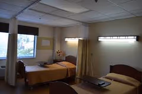Two beds with a privacy curtain in a double-occupancy patient room.