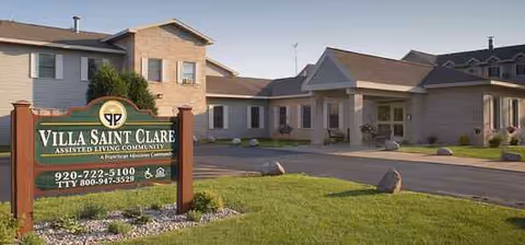 Exterior view of a senior living campus with a sign and beige connected buildings.