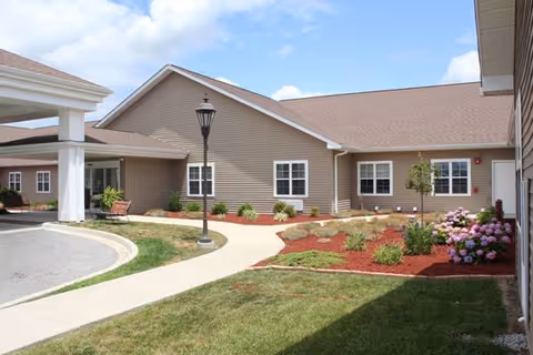 Exterior view of Fox Meadows Supportive Living with walkway, lamppost, and landscaped garden.