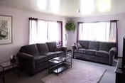 Bright living room with two dark gray sofas, coffee table, and windows.