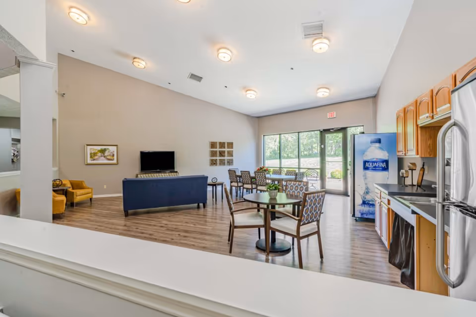 Communal lounge and kitchenette with sofas, dining tables, a TV, and a water vending machine.