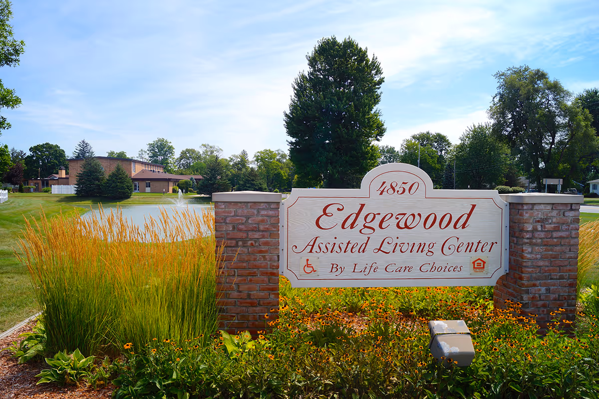 A landscaped entrance sign reading 'Edgewood Assisted Living Center' with a pond and facility building in the background.