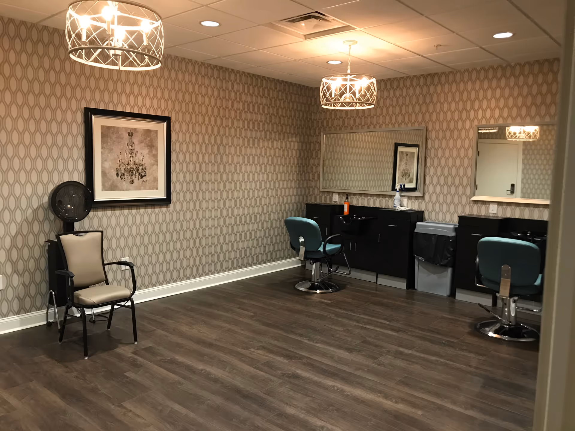 Empty salon-style room with styling chairs, mirrors, and patterned wallpaper.