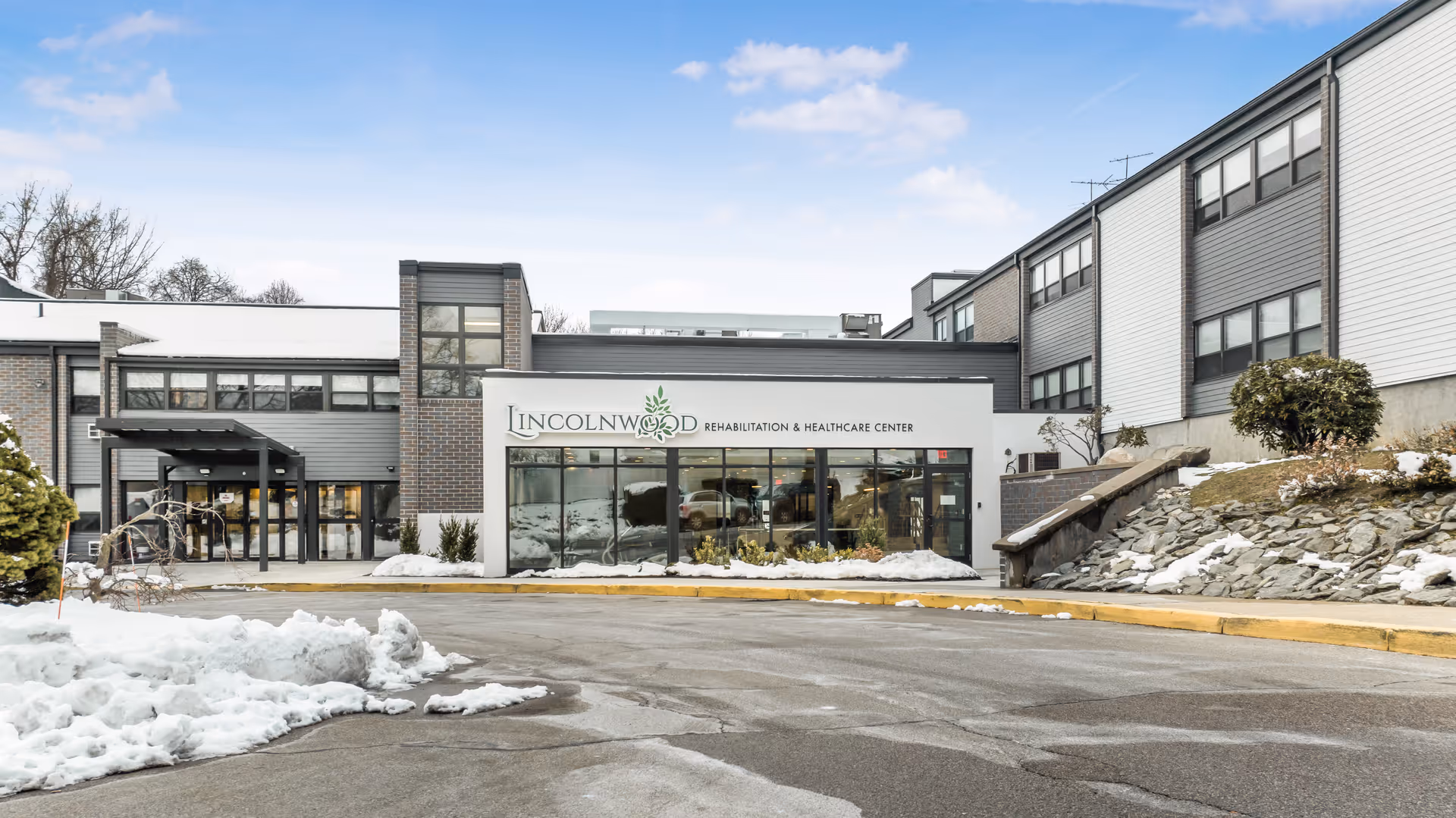 Exterior front view of Lincolnwood Rehabilitation & Healthcare Center building with snow on the ground and a clear sky.
