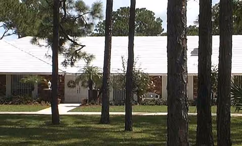 Front view of a single-story Lee Residence facility with a lawn, trees, and entrance.