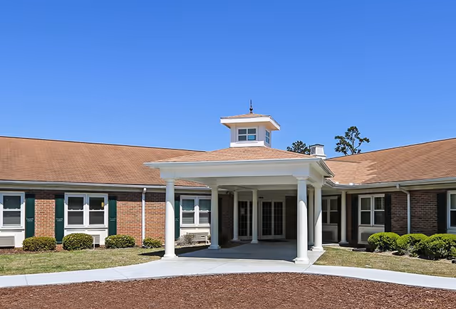 Brick senior living facility exterior with a covered entrance and white columns.