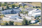 Aerial view of Valley Vista Care facility showing multiple connected buildings with gray roofs surrounded by trees and roads in a suburban area.
