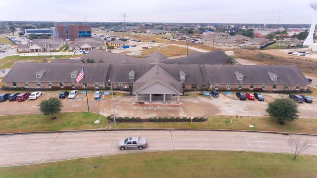 Aerial front view of Mason Creek Transitional Care of Katy building with a drive-up entrance, parked cars, and surrounding grounds.