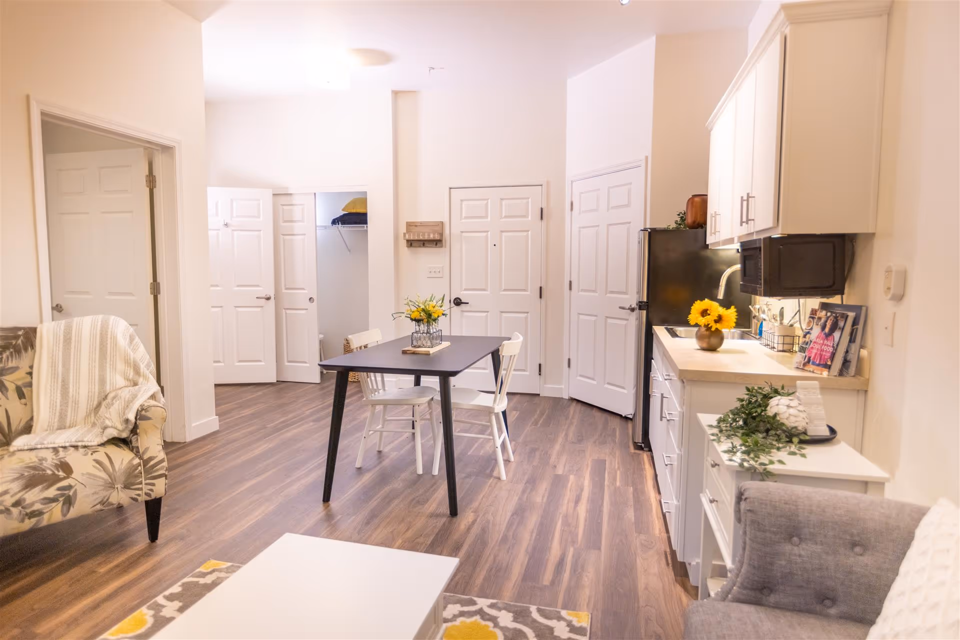 Open-plan living area with a small dining table, kitchenette, and seating.