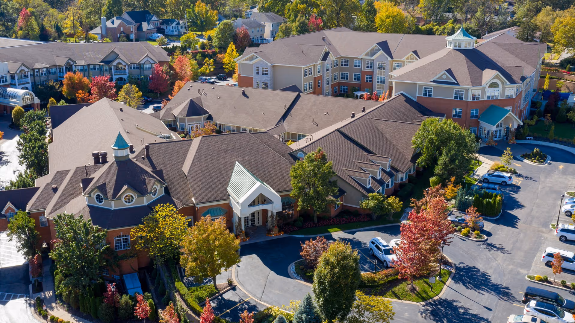 Aerial view of McKnight Place Assisted Living & Memory Care showing the multi-wing building, landscaped entrance circle, and surrounding parking and trees.