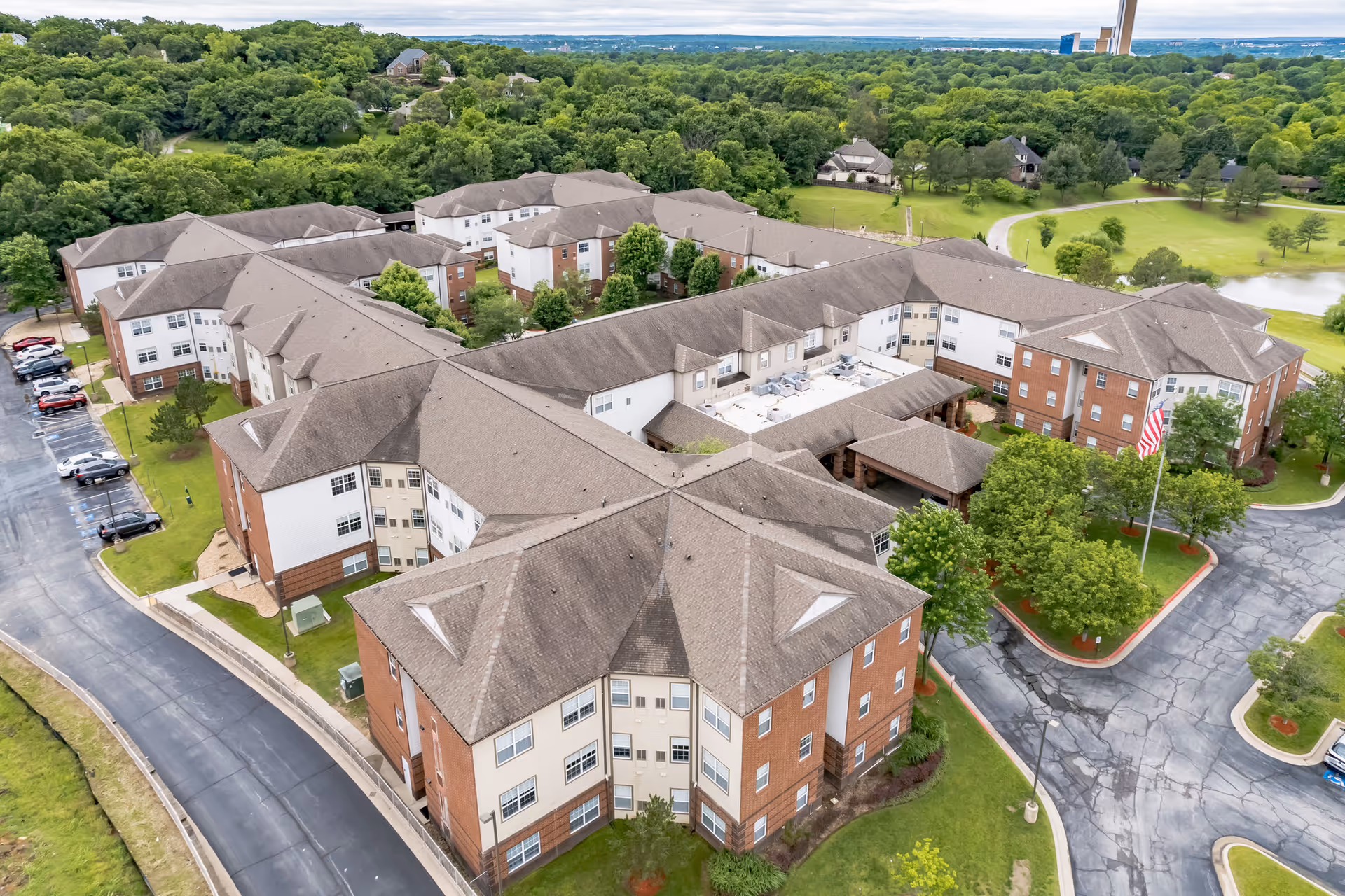 Aerial view of the Town Village Tulsa senior living complex showing multiple connected brick-and-siding buildings, parking areas, and surrounding trees and lawns.