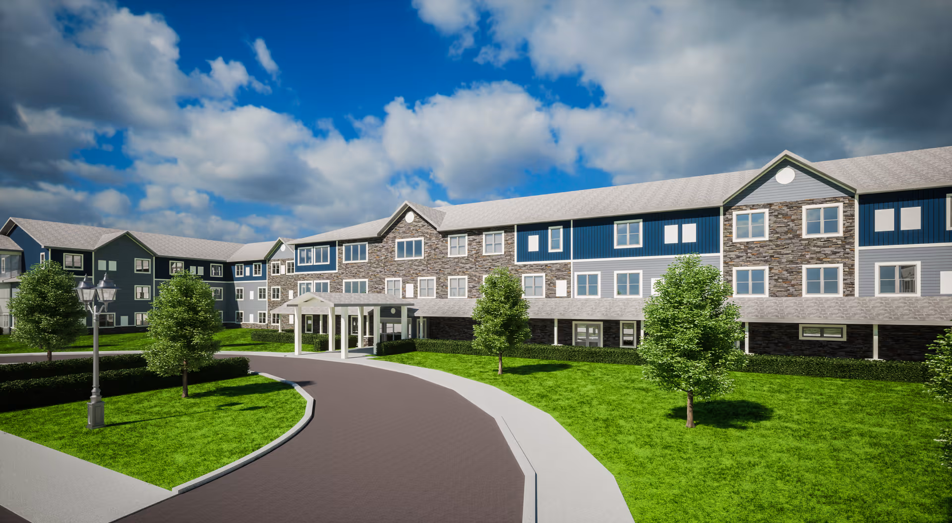 Exterior view of a large, modern senior living facility building with three stories, featuring a combination of stone and blue siding, surrounded by green lawns and trees under a partly cloudy sky.