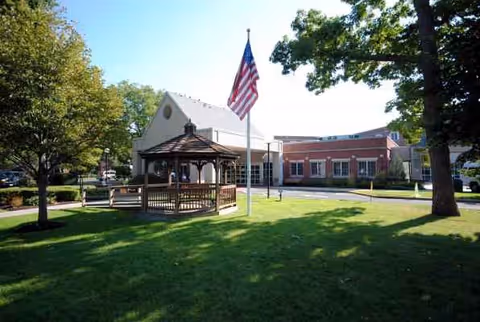 Well-kept lawn with gazebo and flagpole outside Massapequa Center Nursing and Rehabilitation facility.