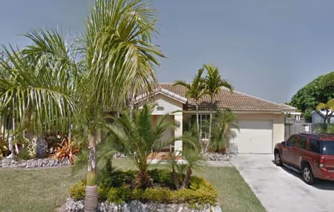 Front exterior of a single-story facility with a garage, driveway, and palm trees.