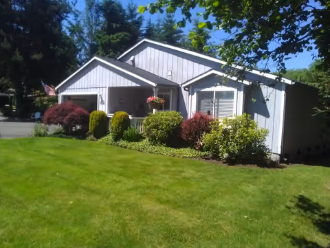 Exterior of a single-story building with a manicured lawn and colorful shrubs.