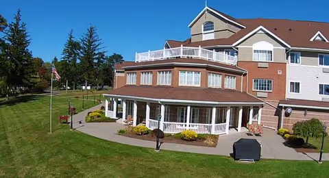 Exterior view of Bishop's Commons at St. Luke, a multi-story senior living facility with a lawn.