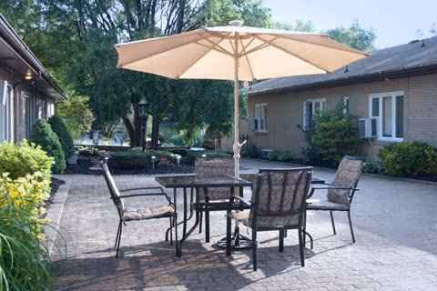 Outdoor patio at Meadow Crest, with table, chairs, and a large umbrella beside a brick building.