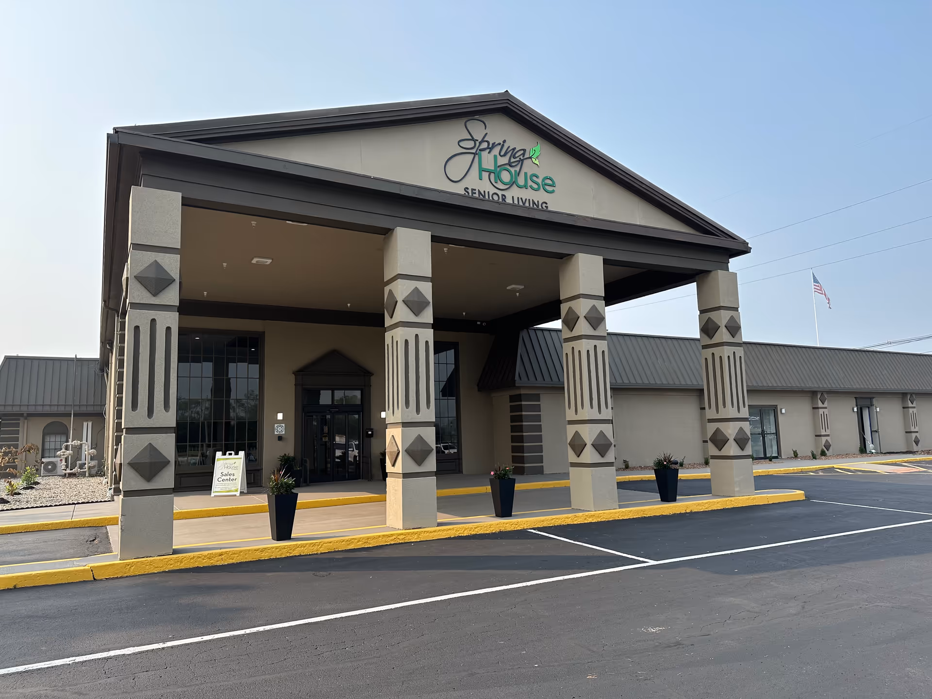 Front entrance of The Spring House senior living facility with a covered porte-cochere supported by decorative pillars.