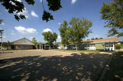 Exterior view of Cornerstone Rehabilitation and Healthcare Center with trees, parking lot, and entrance.