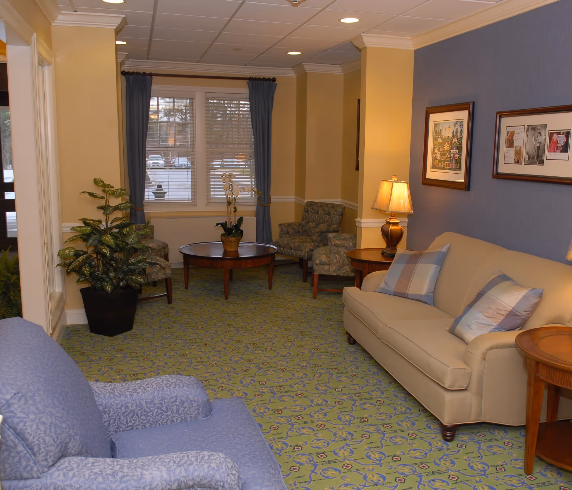 Comfortable sitting room with sofas, armchairs, coffee tables, lamps, framed artwork, and a patterned carpet.