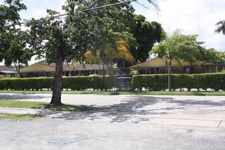 Exterior view of Avalon Park Retirement Residence with trees, hedges, and a front-facing building.