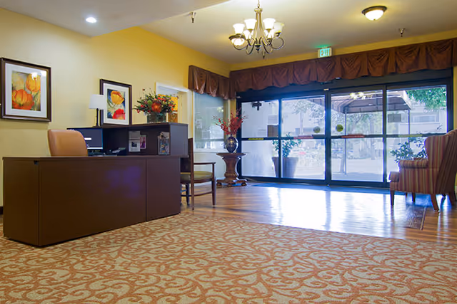Reception lobby with a front desk, seating, artwork and glass entrance doors.