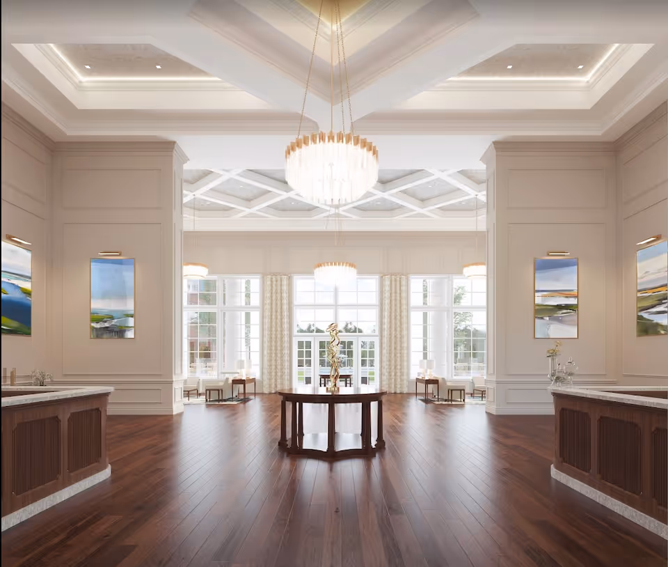 Bright, elegant senior living lobby with a central round table, chandeliers, wood floors, and large windowed entrance.