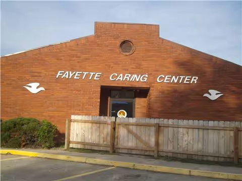 Brick Fayette Caring Center building facade with a small wooden fence in front