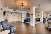 Open, elegantly furnished senior living facility interior with seating, columns, chandeliers and a dining area.