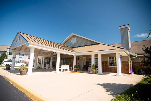Exterior view of Brookdale Staunton entrance with covered drop-off, white columns, and seating.