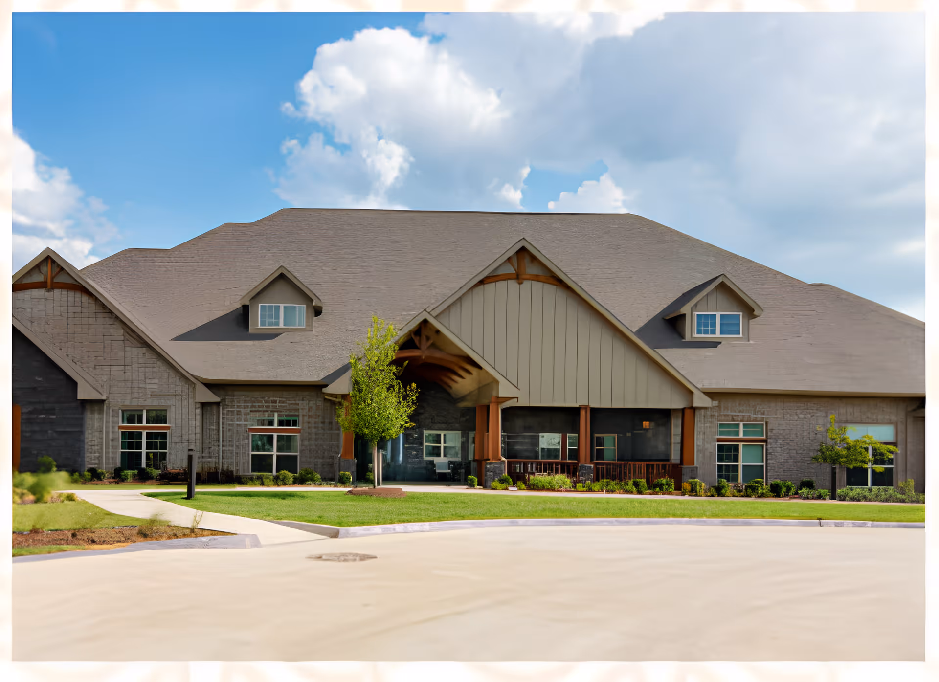 Front exterior of a single-story senior living facility with a large gabled roof, covered entrance, and landscaped lawn.