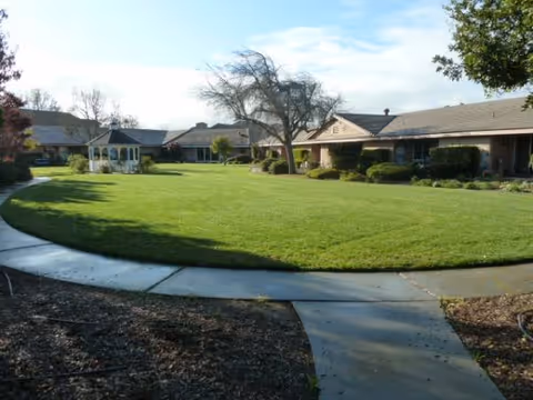 Curved walkway surrounds a well-kept green lawn in front of a single-story facility.