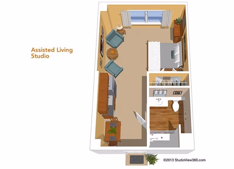 3D floor plan of an assisted living studio apartment showing a combined living and sleeping area with two armchairs, a round table, a bed, a dresser, and a window with curtains. The kitchen area includes cabinets, a sink, and appliances. There is a separate bathroom with a sink, toilet, and shower. A small entryway with a plant is also visible.