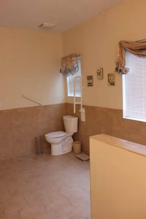 Accessible bathroom with toilet, grab bar, and tiled walls in a senior living facility.