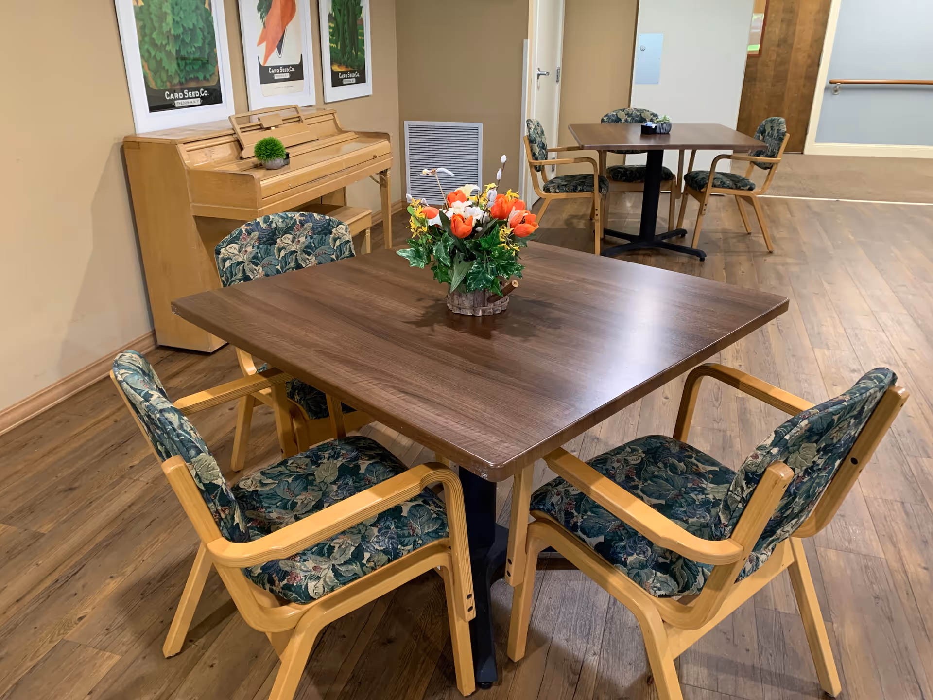 Interior dining area with wooden tables, floral chairs, and a flower centerpiece.
