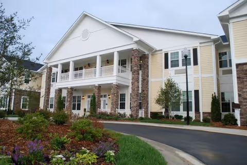 Exterior view of Carillon Assisted Living of Clemmons building with stone columns and landscaping.