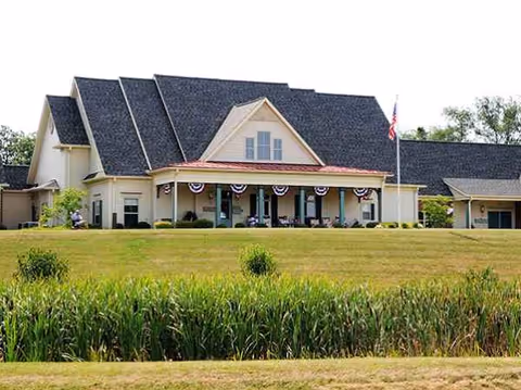 Front view of Columbia Cottage senior living building with bunting, flag, and manicured lawn.