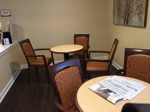Interior seating area in a senior living lounge with round tables and chairs.