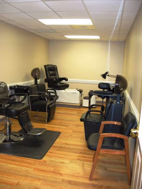 Interior salon area with black styling chairs and hair-drying equipment.