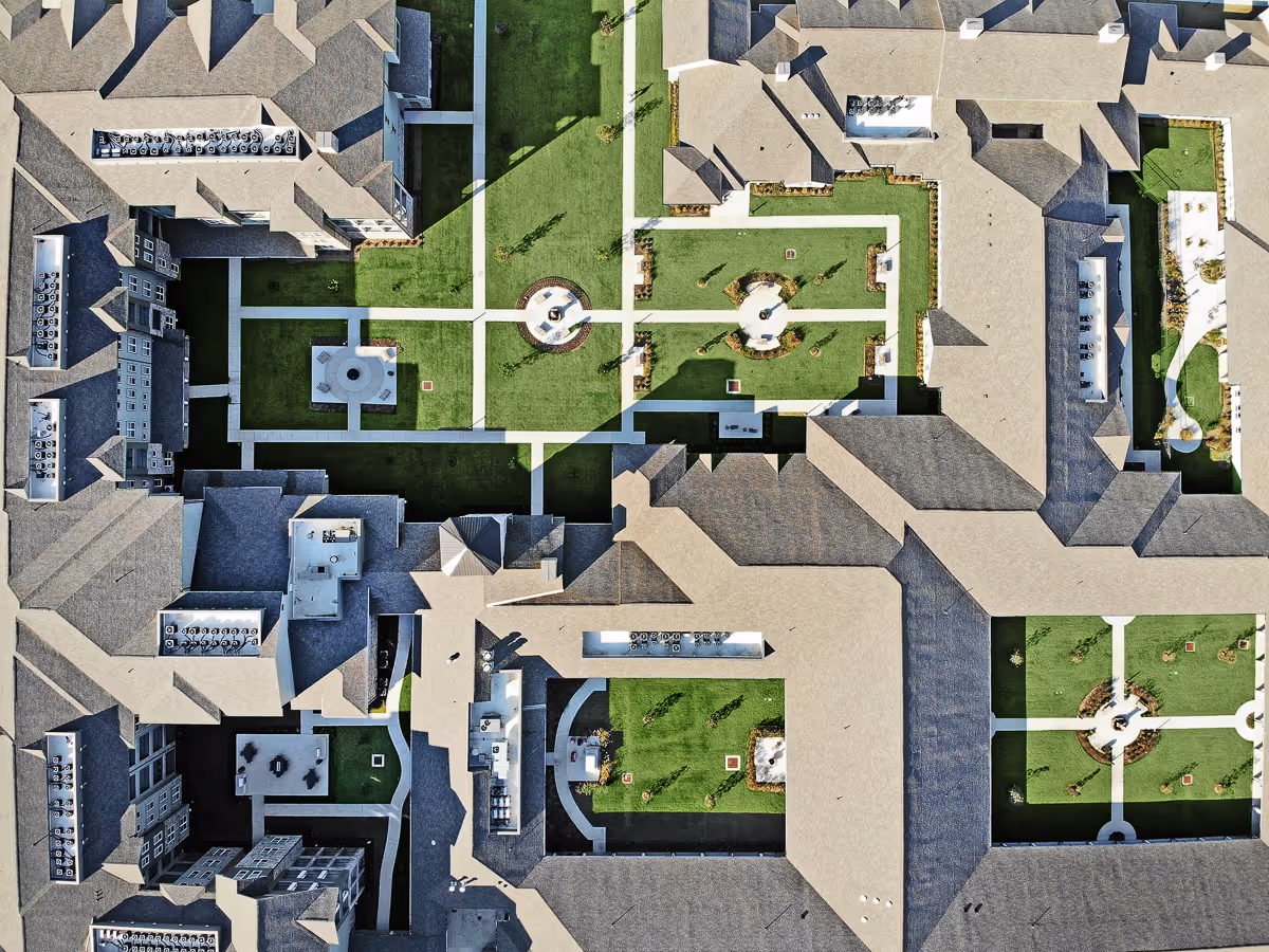 Aerial view of interconnected buildings surrounding multiple landscaped courtyards with walkways and circular fountains.