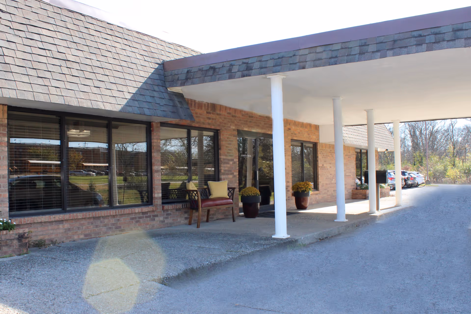 An exterior view of the Whites Creek Wellness & Rehabilitation Center featuring brick walls, large windows, and a canopy entrance.