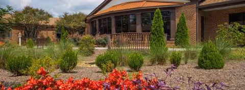 Front view of White Oak Estates building with landscaped shrubs and vibrant flowers.