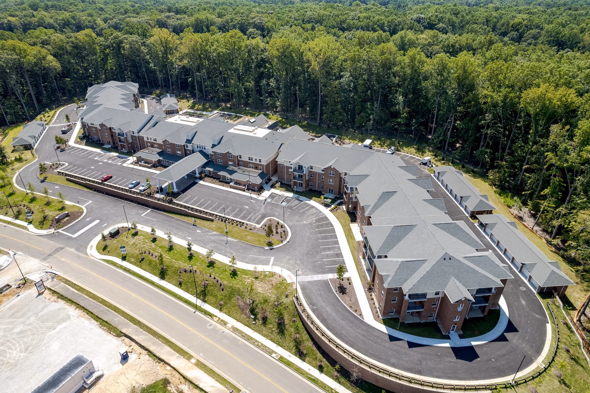 Aerial view of the Virginia Greens Retirement Community building with parking areas and surrounding woods.