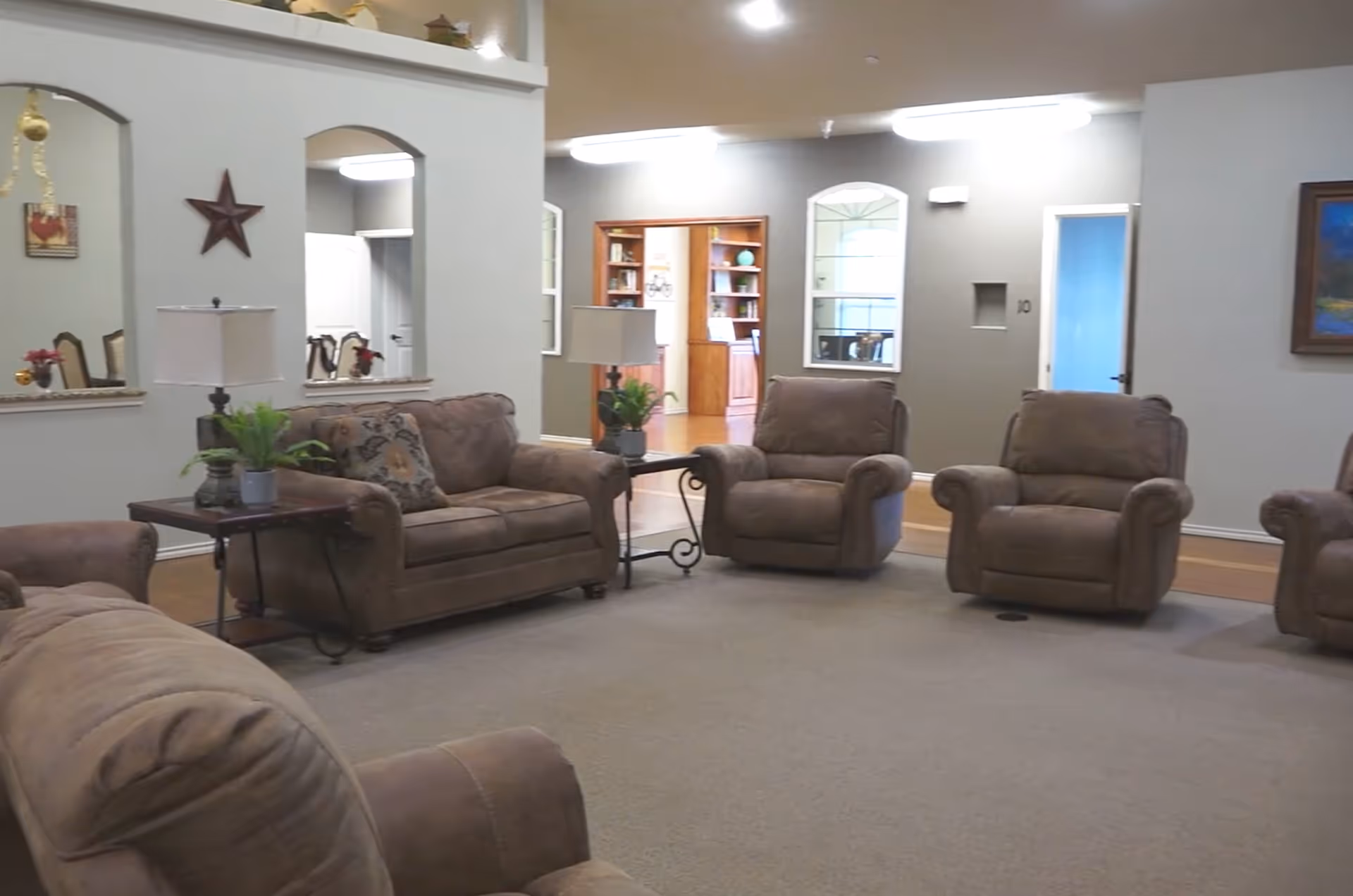 Spacious common room with several brown upholstered recliners and a sofa arranged around side tables and lamps.
