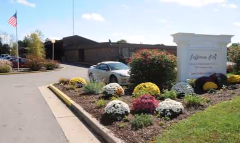 Exterior view of Jefferson City Nursing and Rehab entrance with landscaped flower beds.