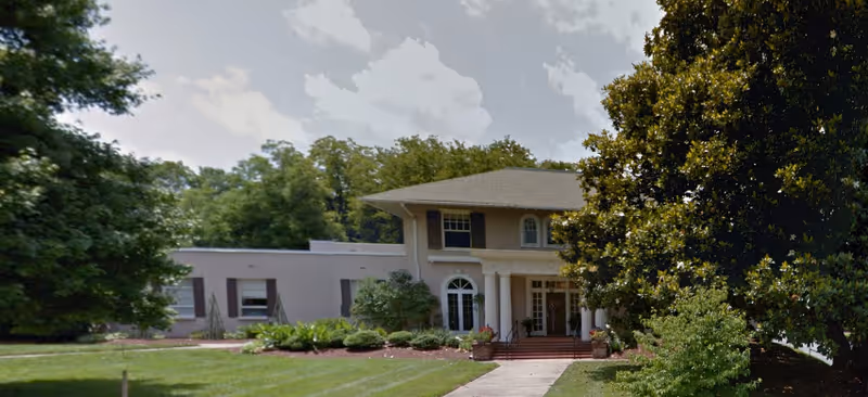 Two-story Boston Commons senior living facility front with arched entrance and well-kept landscaping.